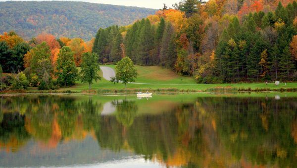A lake surrounded by trees with autumn leaves reflected in the water.