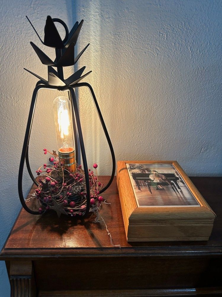 A pineapple lamp is sitting on a wooden table next to a picture frame.