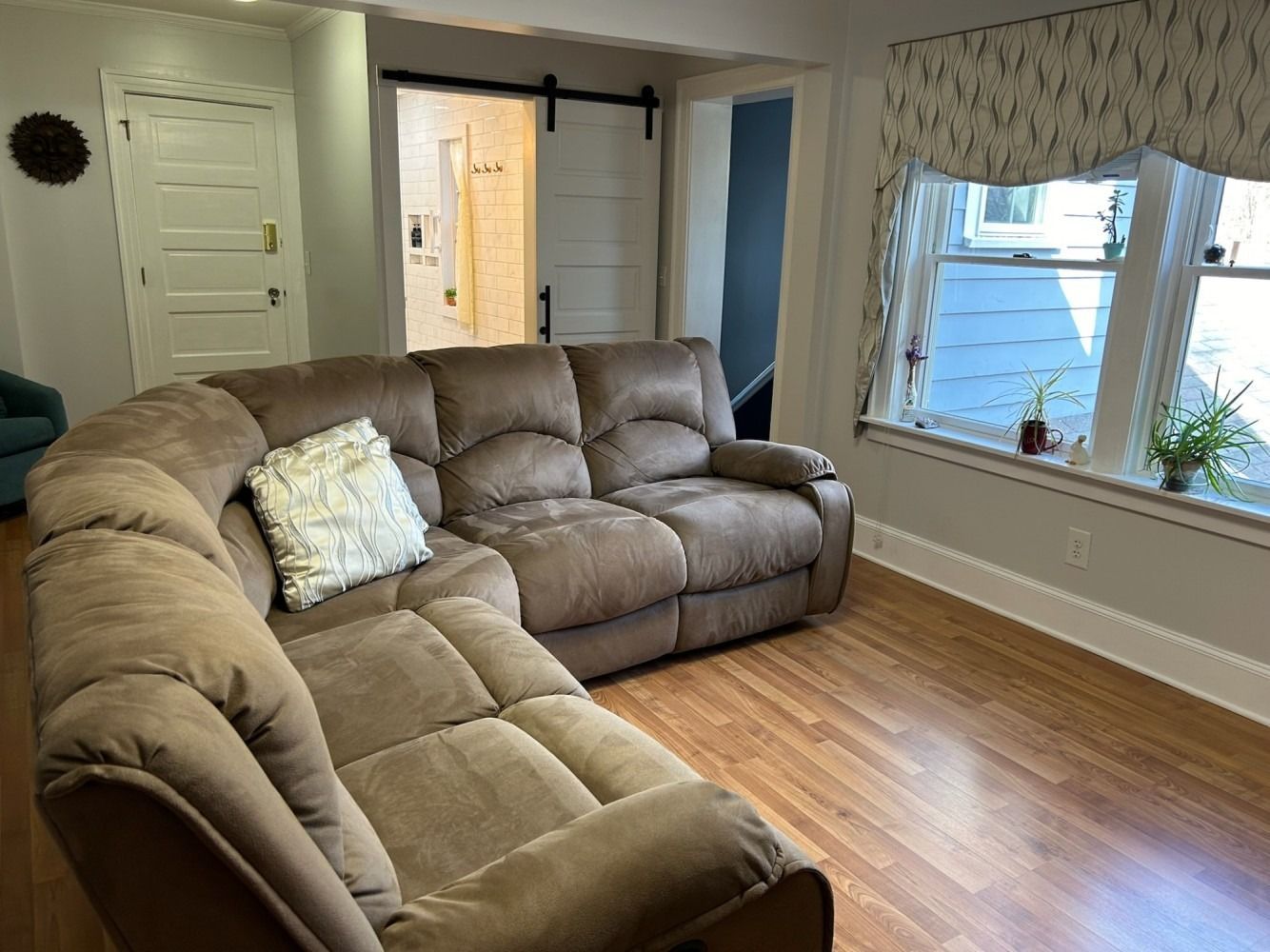 A living room with a large sectional couch and a window.