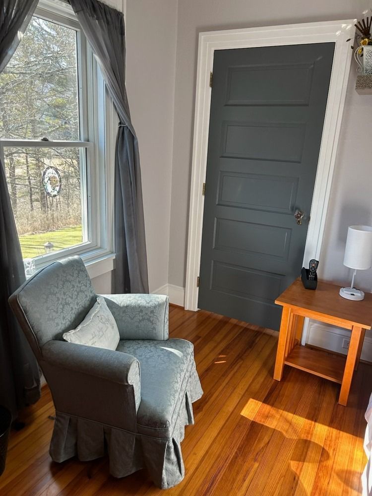 A chair is sitting in a room next to a window and a door.