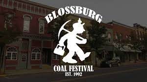 A logo for the blossburg coal festival is displayed in front of a brick building.