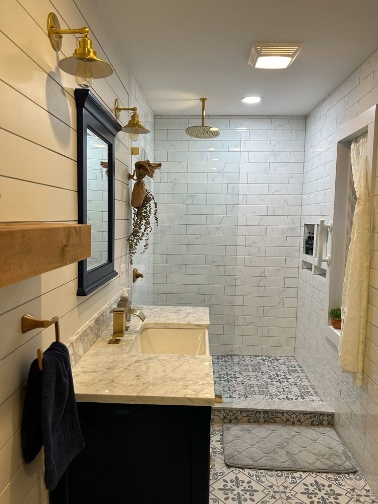 A bathroom with a sink , mirror , and walk in shower.