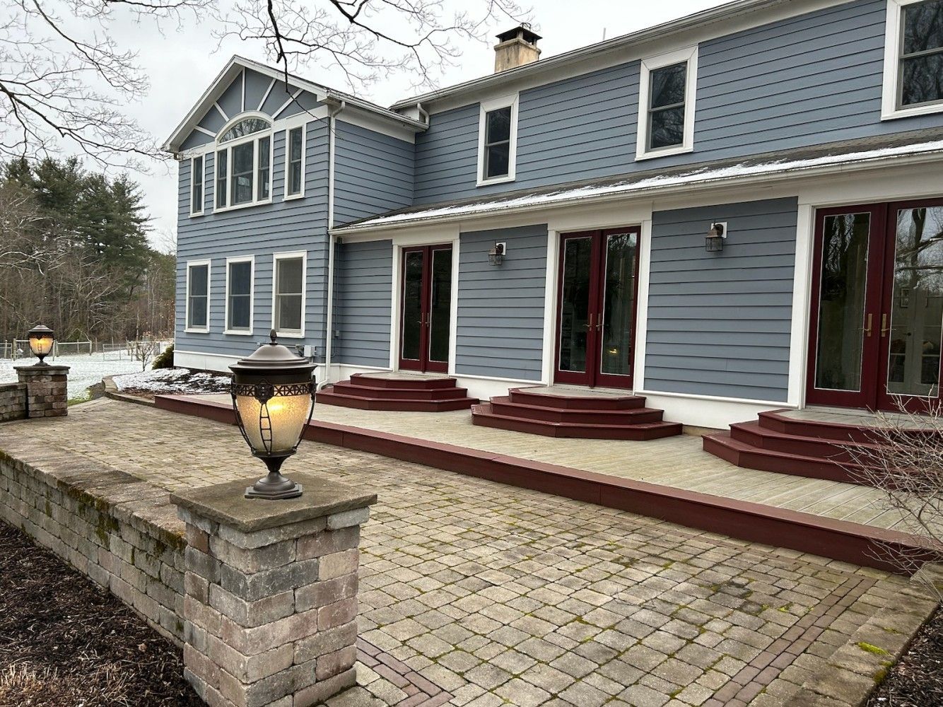 A large blue house with a brick patio in front of it.