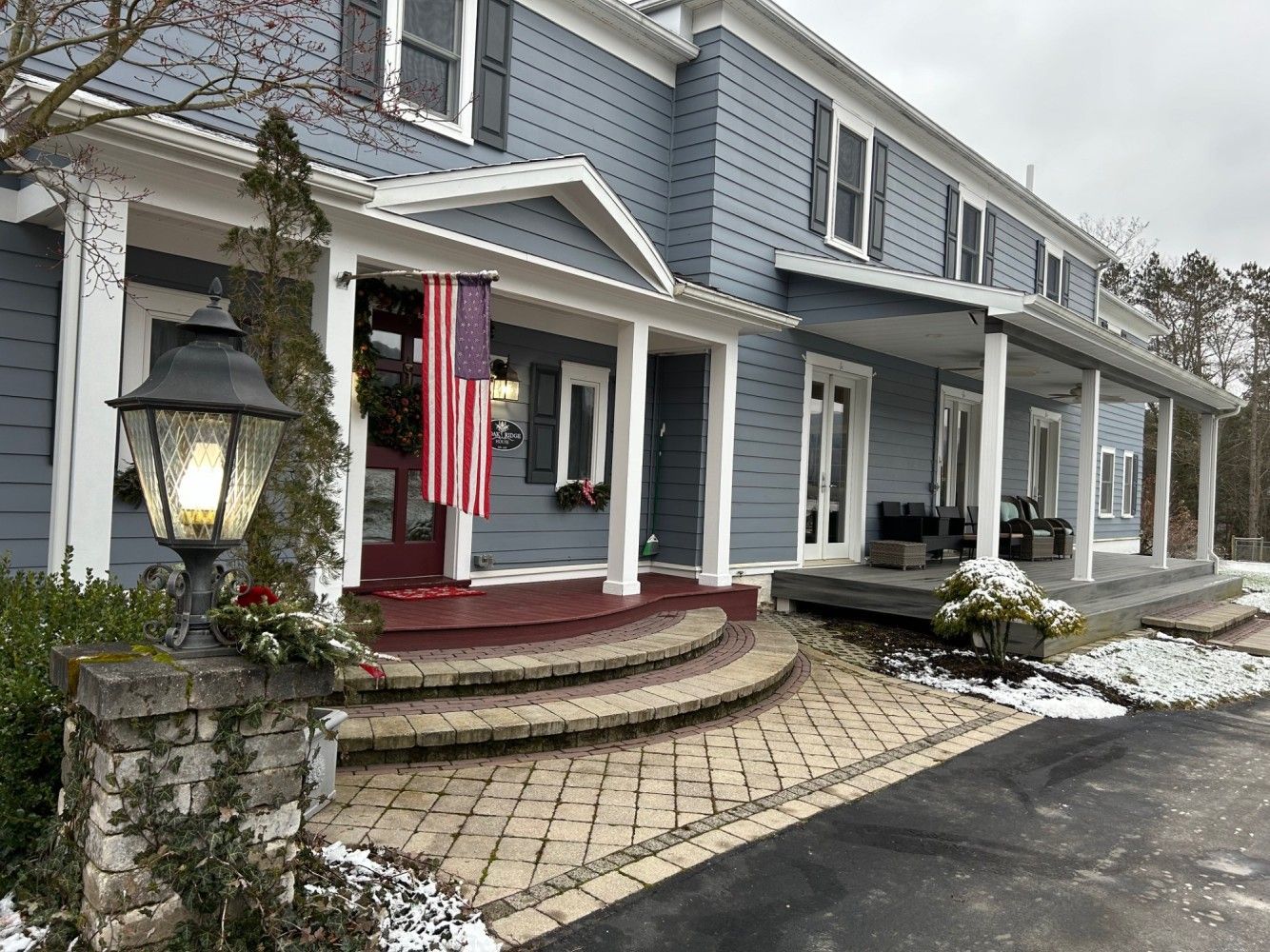 A large blue house with a large porch and an american flag on it.