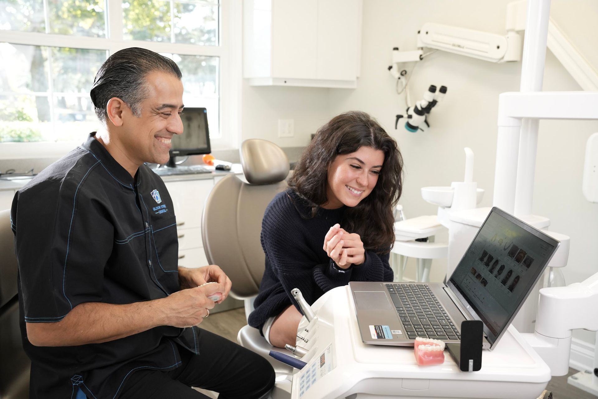 a dentist talks to a patient who is looking at a laptop | Bloor Street Dental | Best Family and Cosmetic Dentist In Mississauga For Implants, Braces, and Invisalign