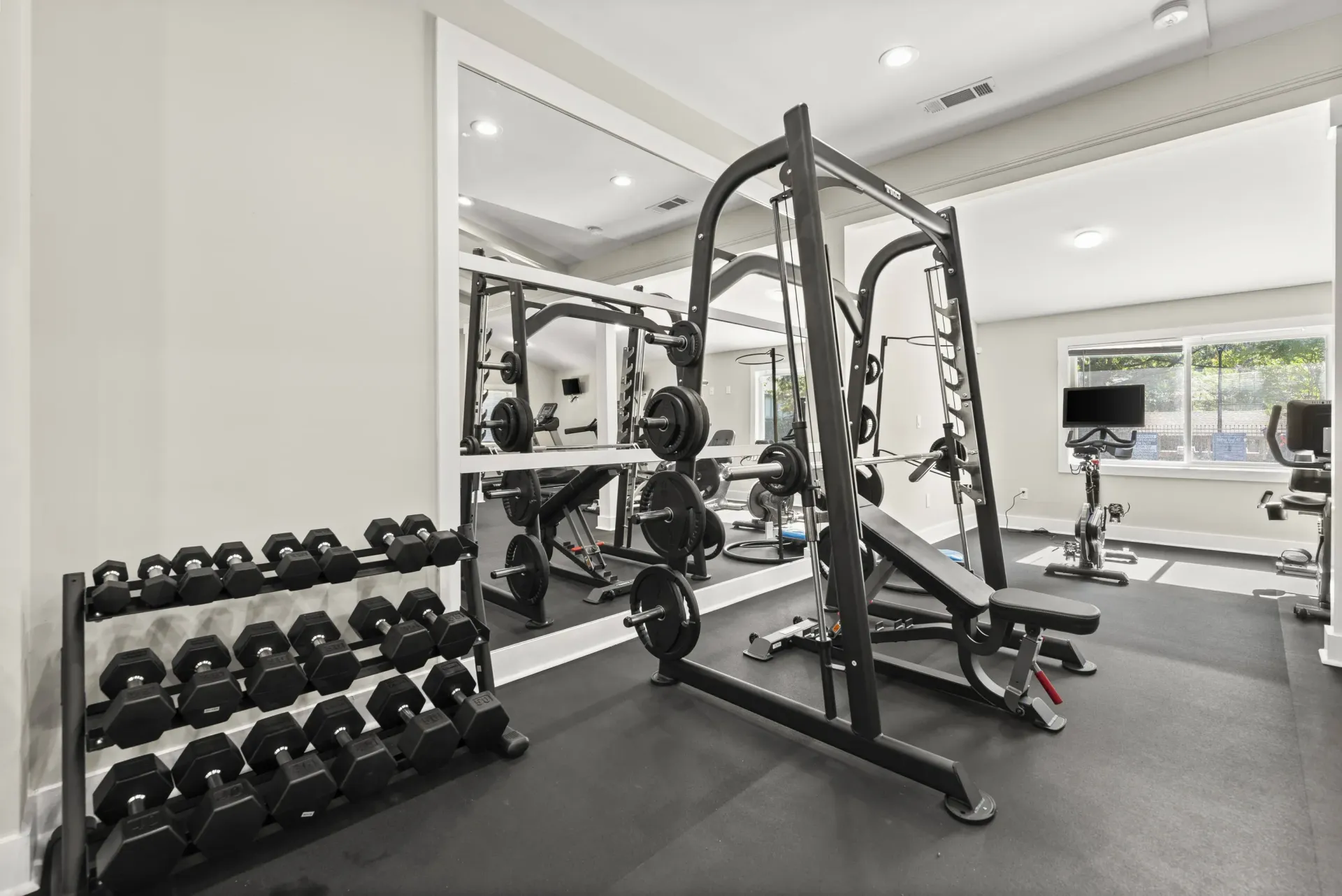 A gym with a variety of equipment including dumbbells, a bench press, and a squat rack.