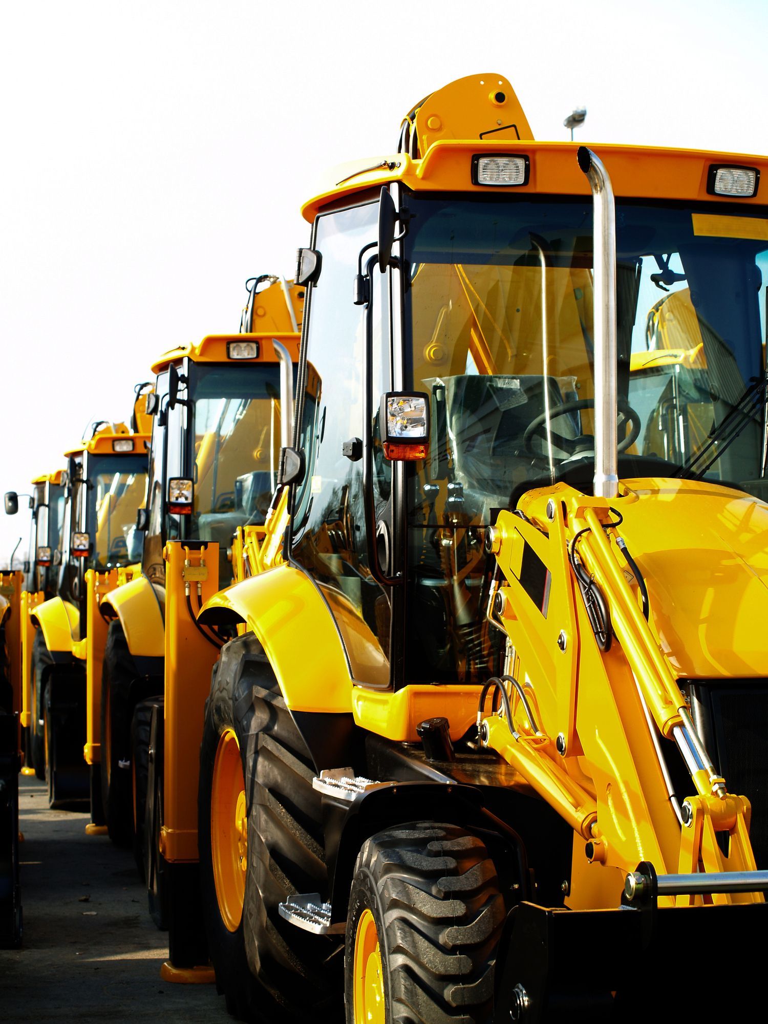 A row of yellow tractors are parked next to each other