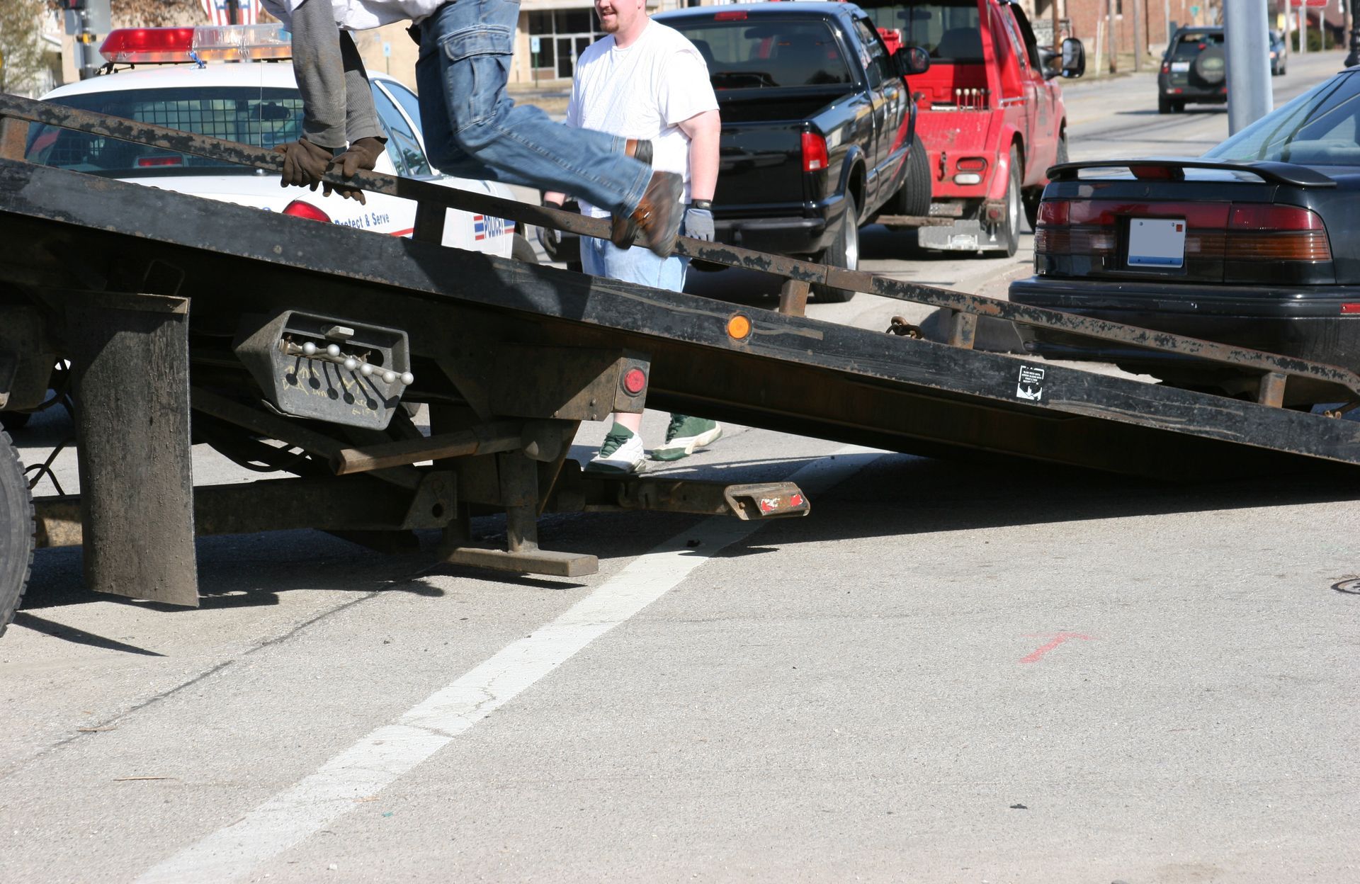 A man sits on a tow truck with a license plate that says ' jc ' on it