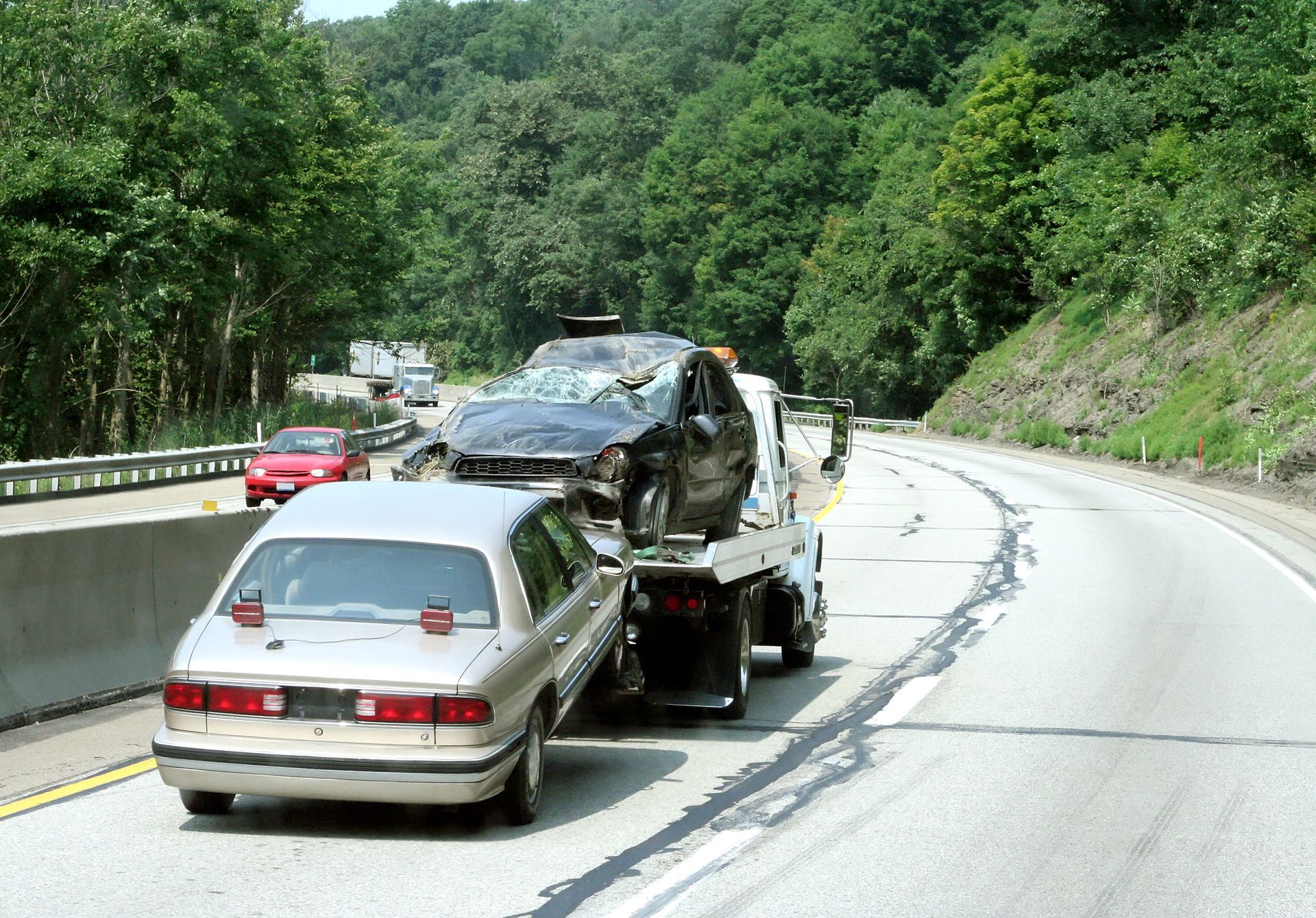 A car is being towed down a highway by a tow truck