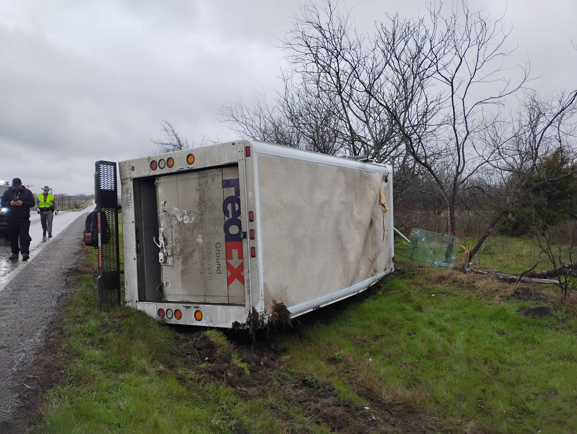 A fedex truck has turned over on the side of the road. A fedex truck has turned over on the side of the road.