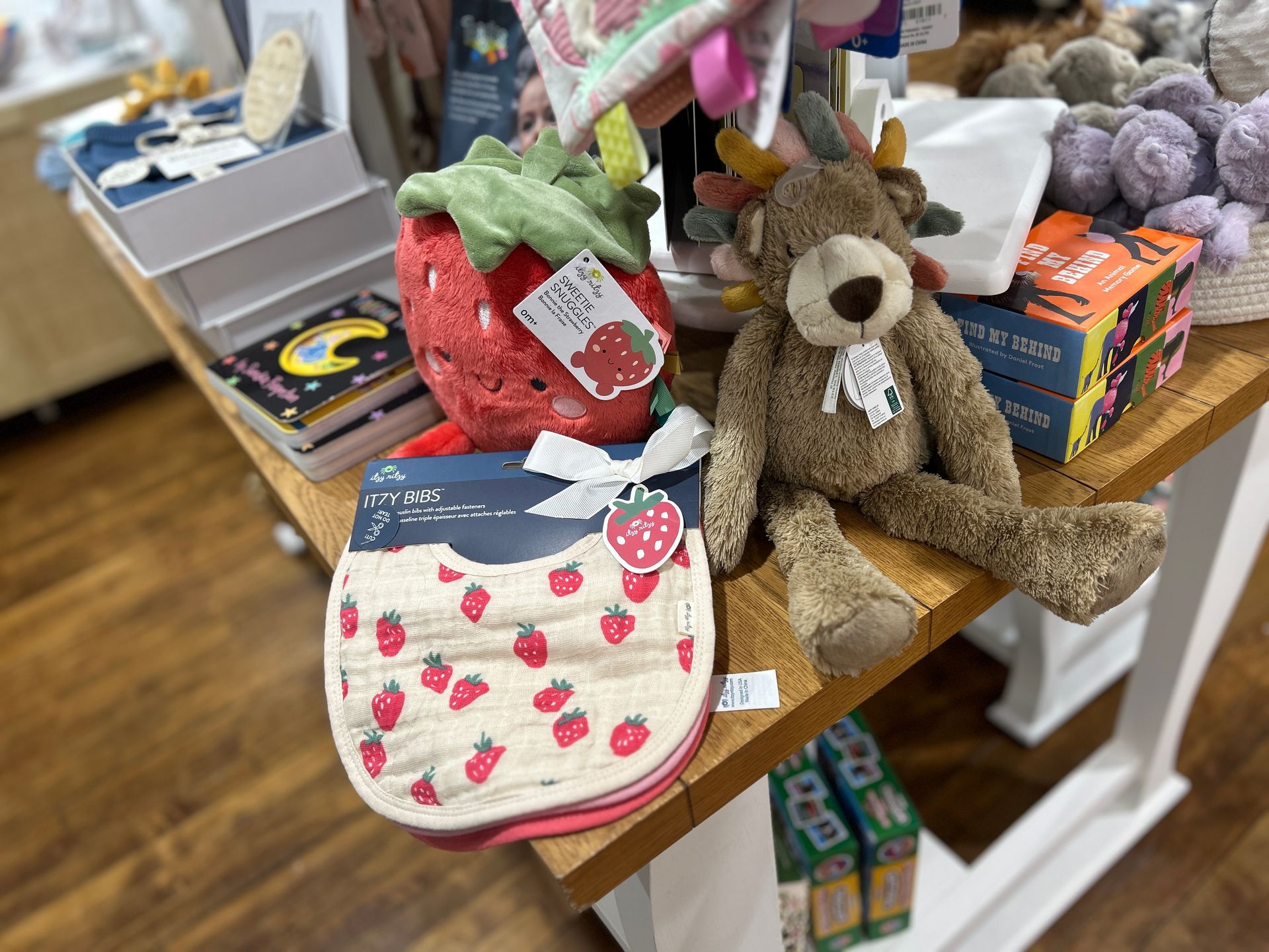 Stuffed animals and small bags displayed on a wooden table in a shop.