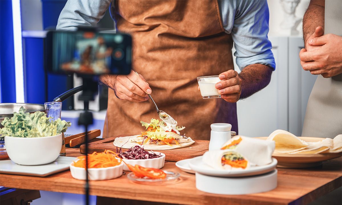 A man is cooking food in front of a camera.