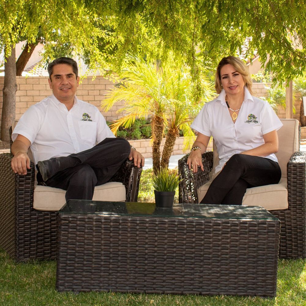 A man and a woman are sitting in wicker chairs next to a table