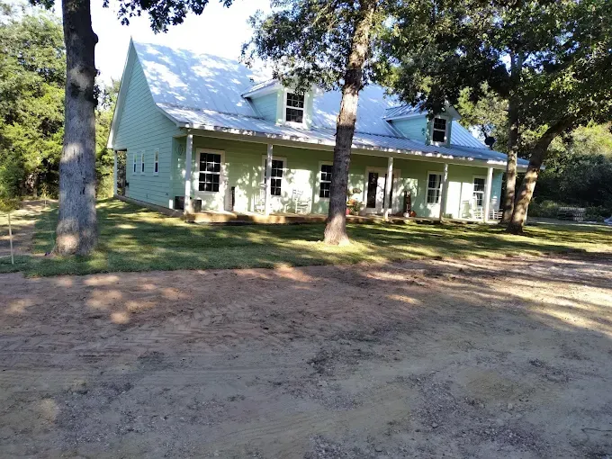 A white house with a porch and trees in front of it