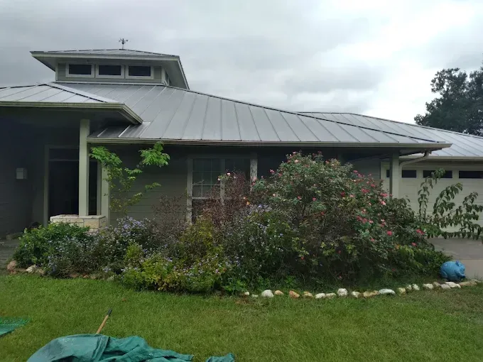 A house with a metal roof and a green tarp in front of it