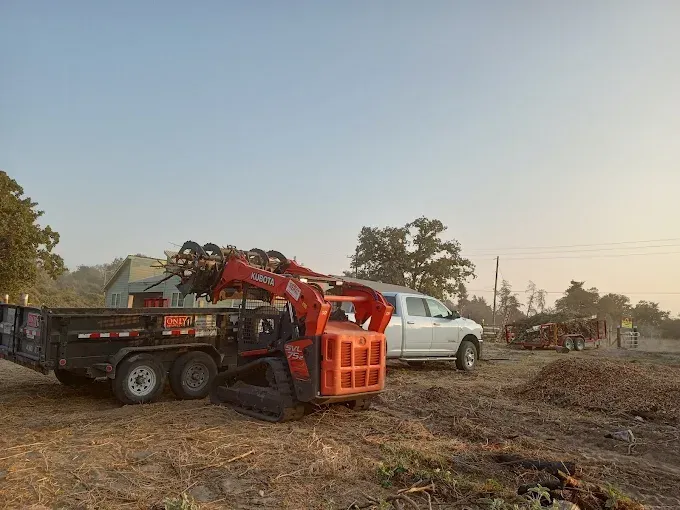 A white truck is parked next to a trailer with a crane on it.