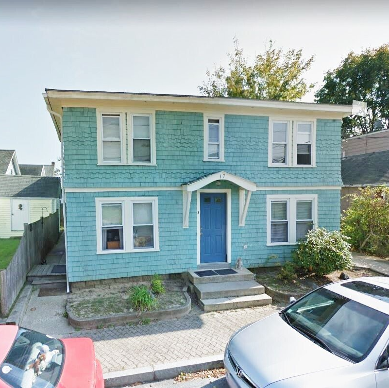A blue house with a blue door and a red car parked in front of it