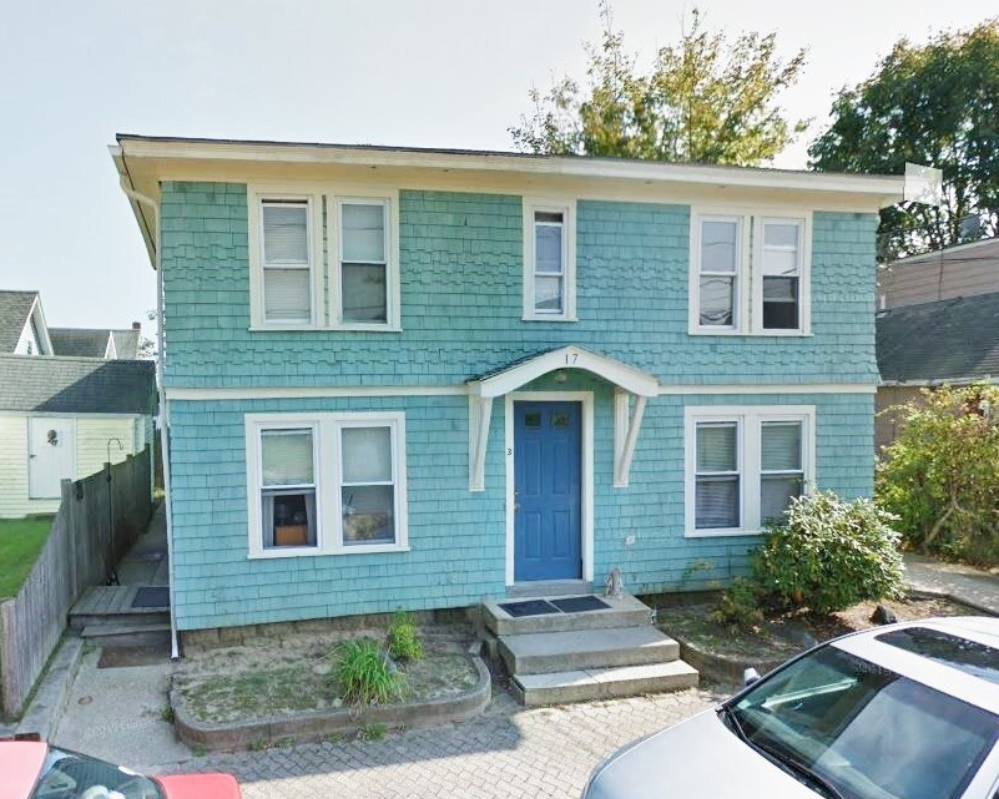 A blue house with a blue door and a red car parked in front of it