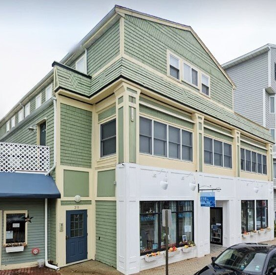 A green and white building with a car parked in front of it