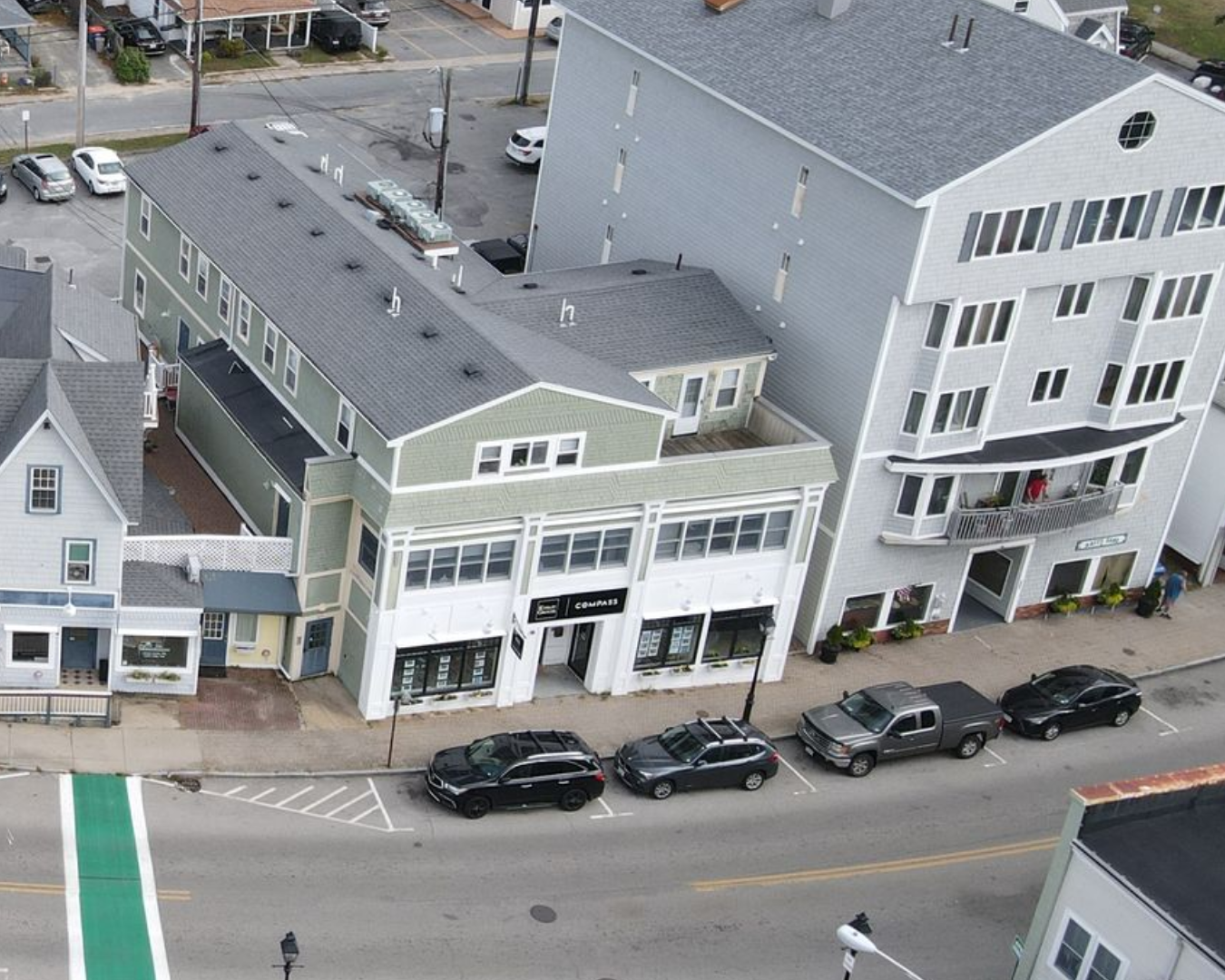 A green and white building with a car parked in front of it