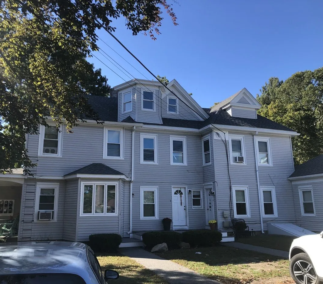 A large white house with a car parked in front of it.