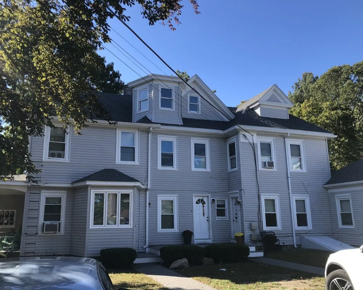 A large white house with a car parked in front of it.