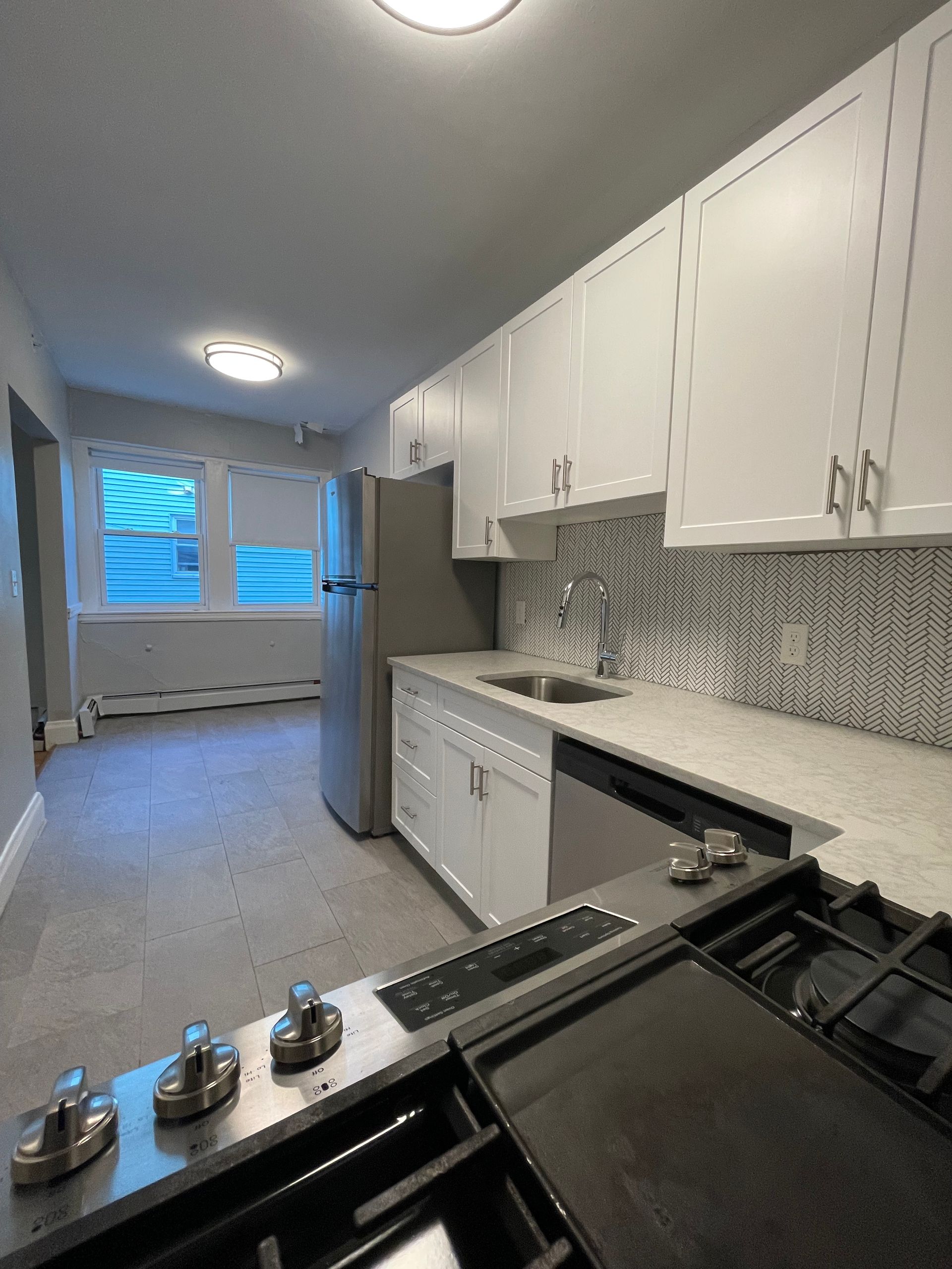 A kitchen with white cabinets and a stove top oven