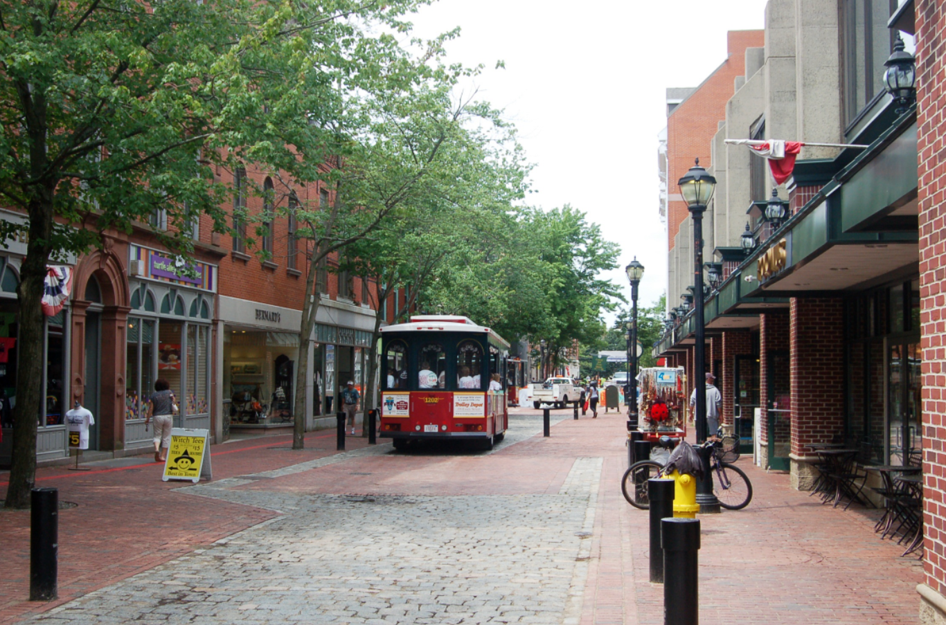 A red bus is driving down a cobblestone street