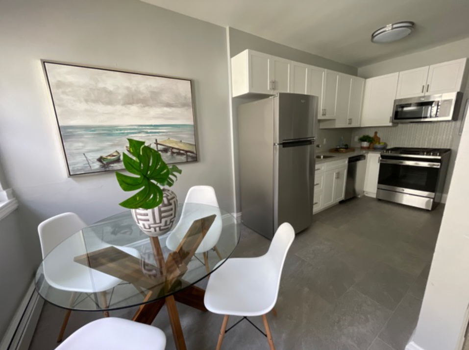 A kitchen with a glass table and chairs and a painting on the wall