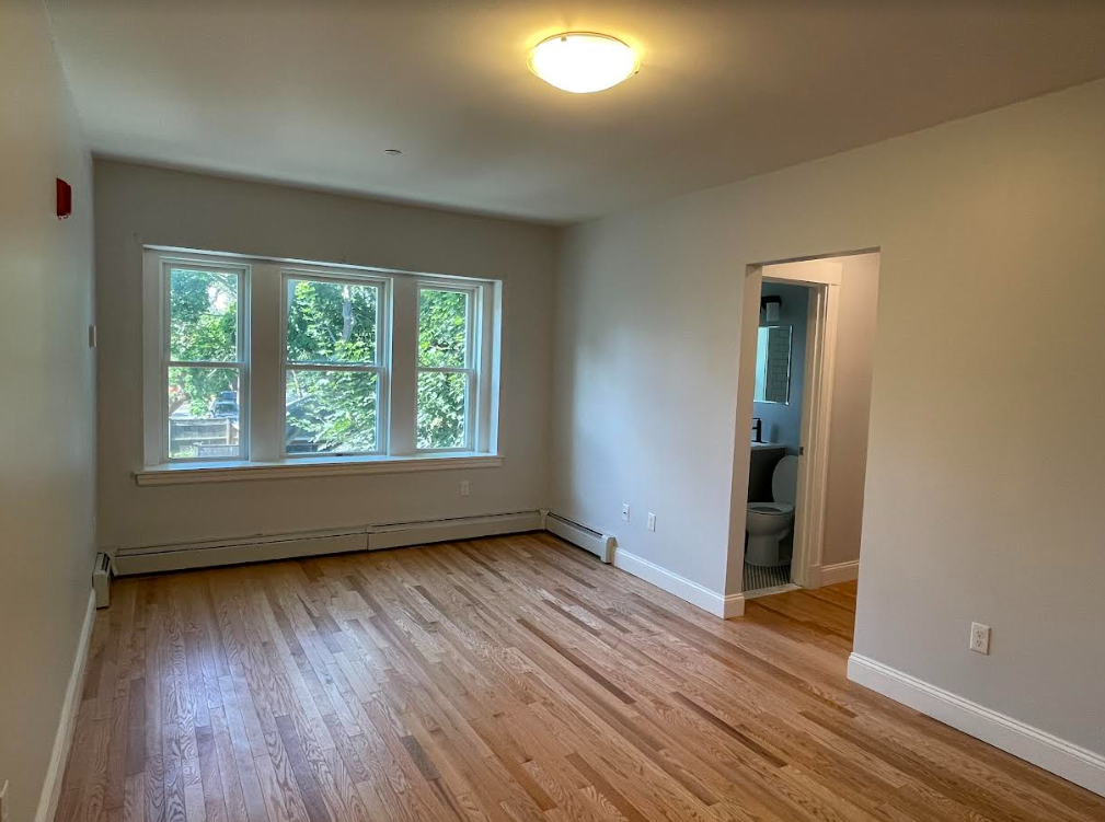 An empty room with hardwood floors and a window