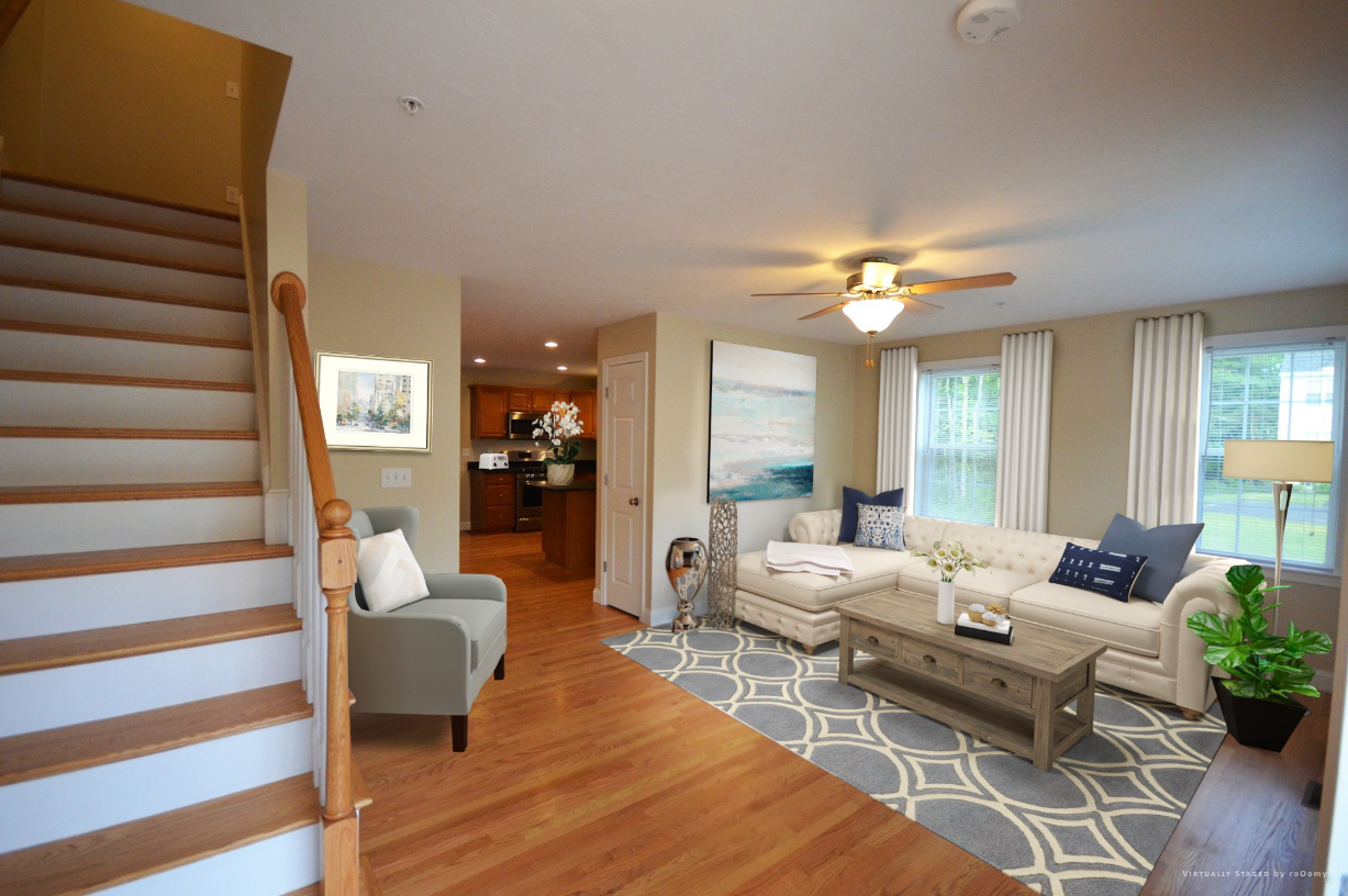 A living room with a couch , chair , coffee table and stairs.