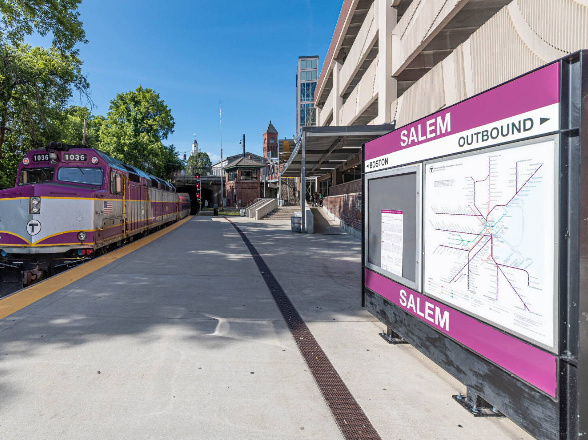 A train is sitting at a train station next to a sign.