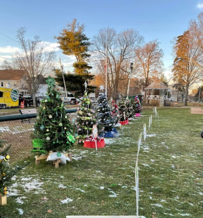 A row of christmas trees are sitting on top of a lush green field.