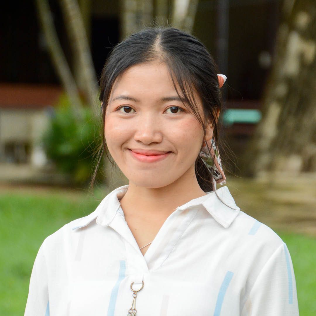 A young woman in a white shirt is smiling for the camera.