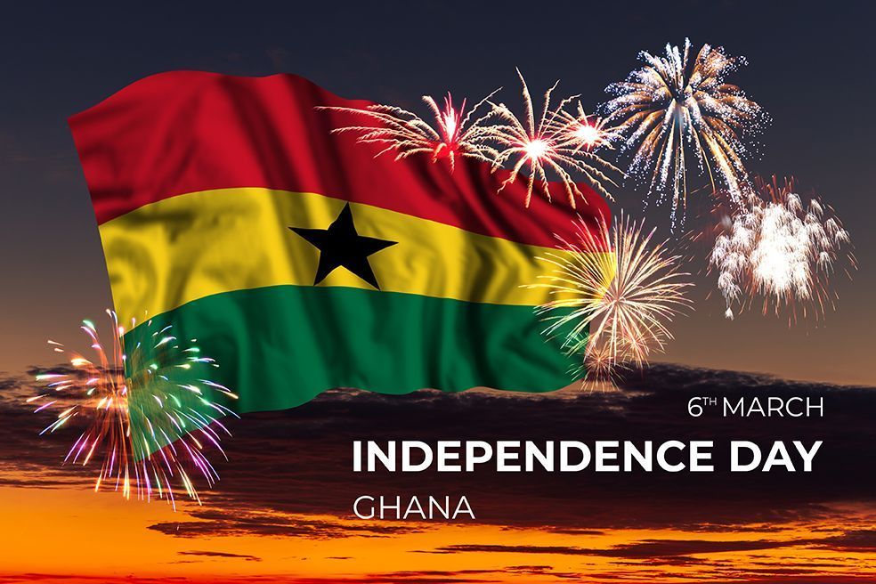 The flag of ghana is waving in the wind with fireworks in the background