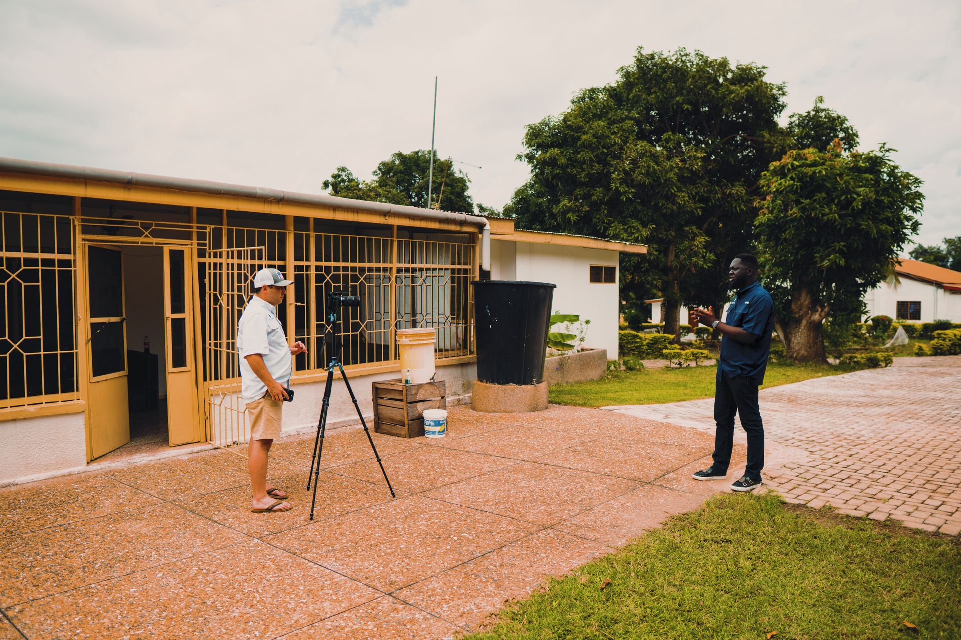 Two men are standing in front of a building talking to each other.