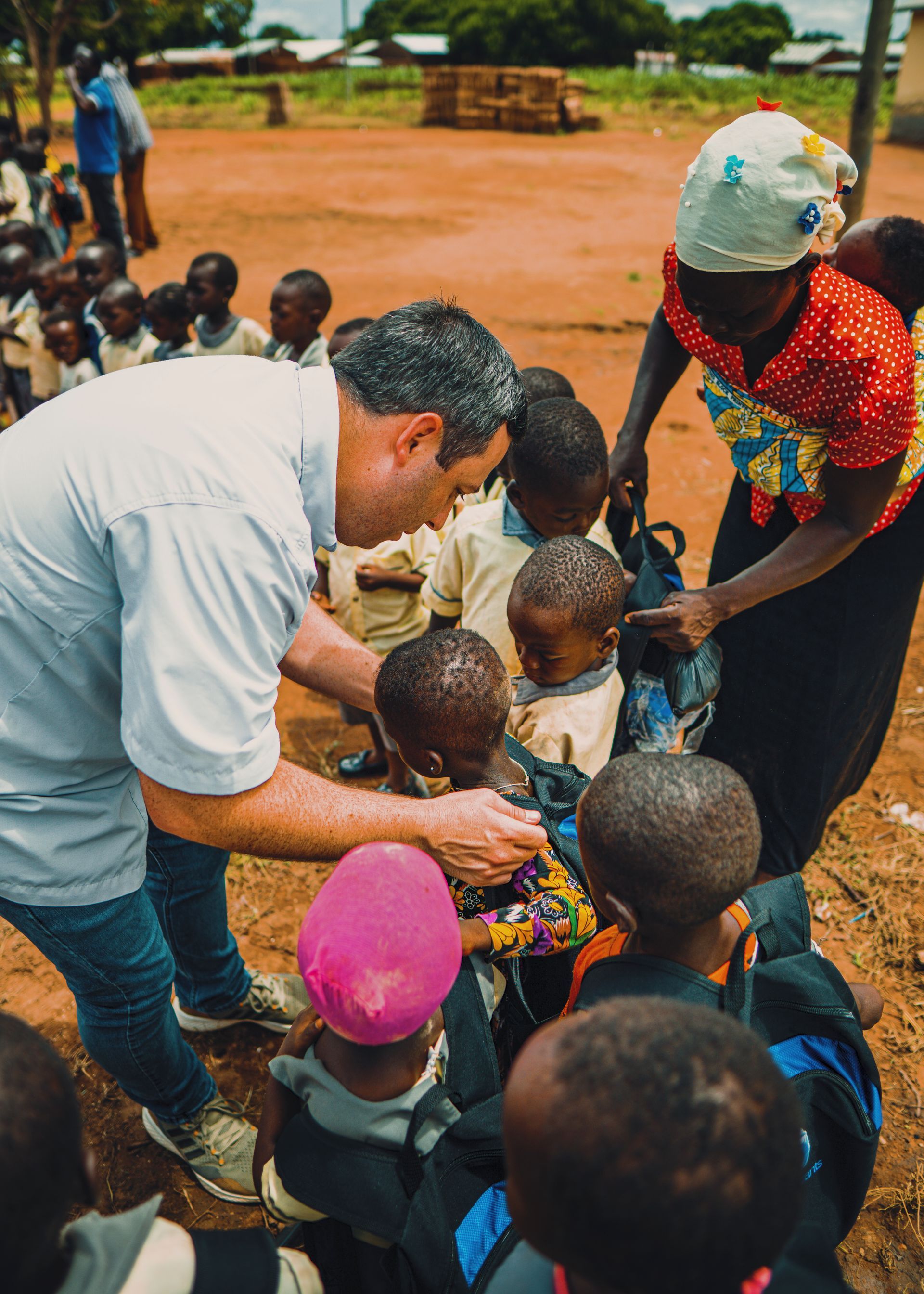 A man is talking to a group of children in a field.