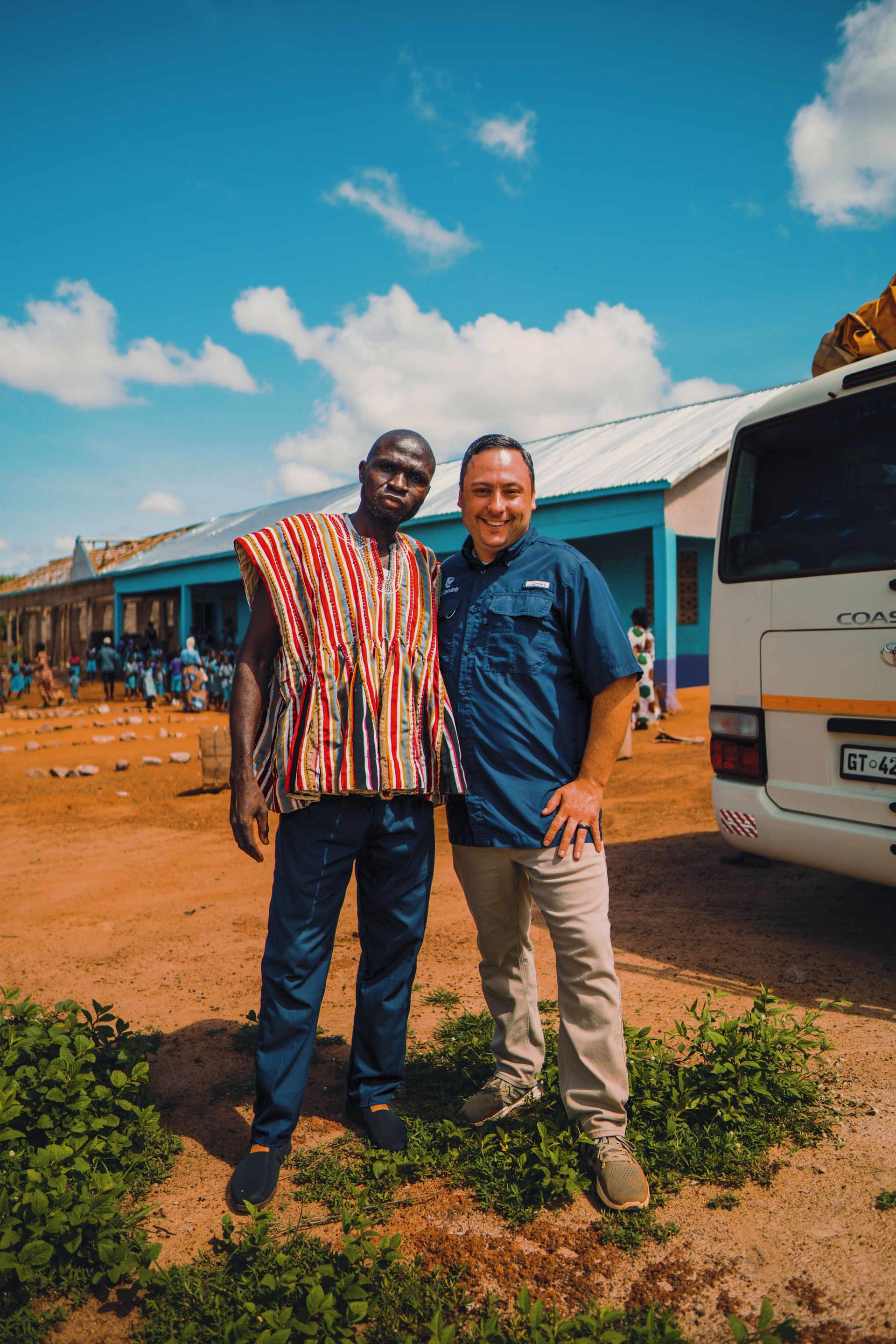 Two men are standing next to each other in front of a van.