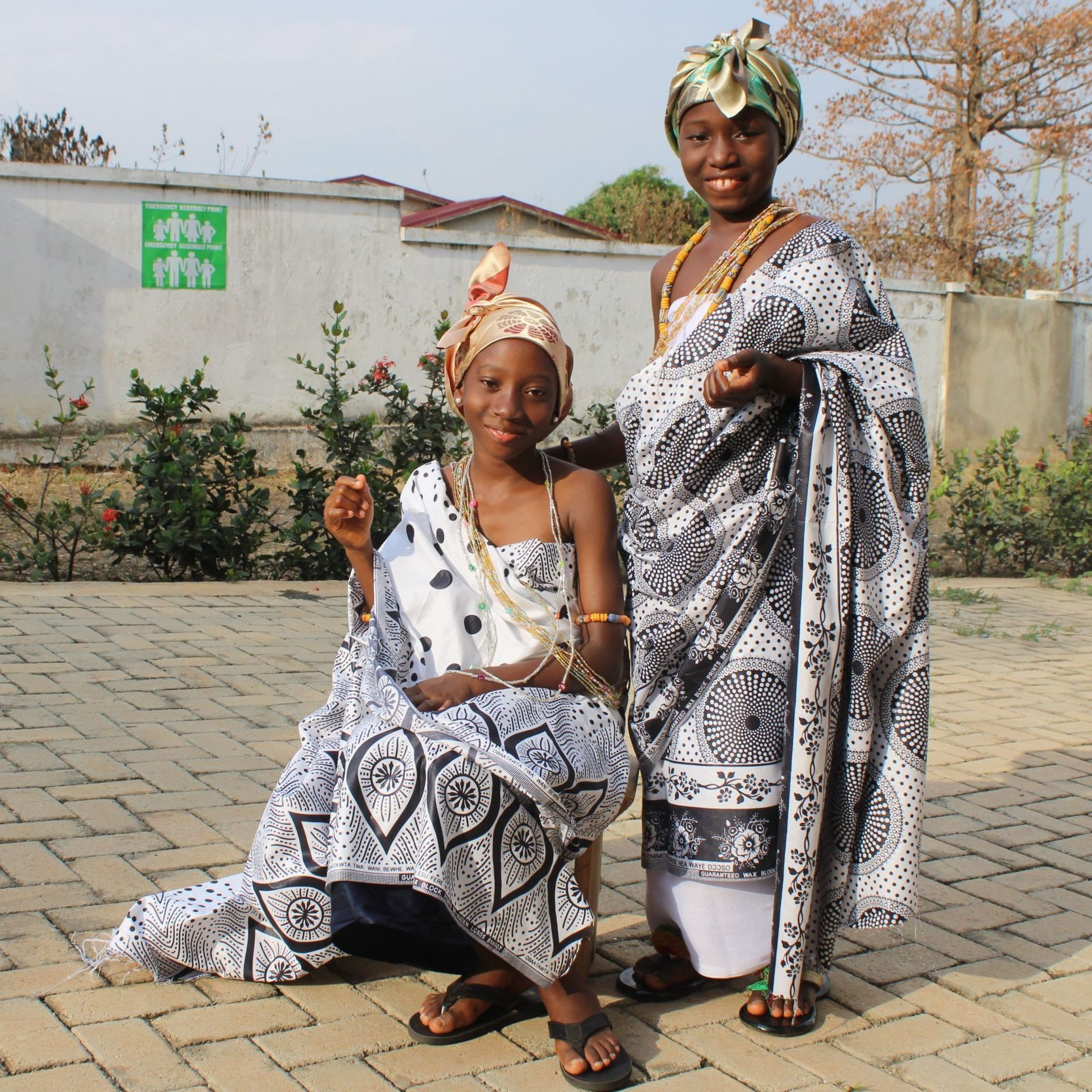 A couple of girls standing next to each other in front of a green exit sign