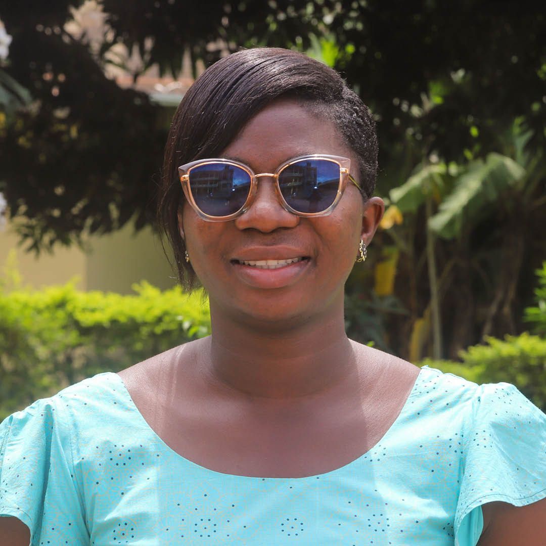 A woman wearing sunglasses and a blue shirt is smiling for the camera.