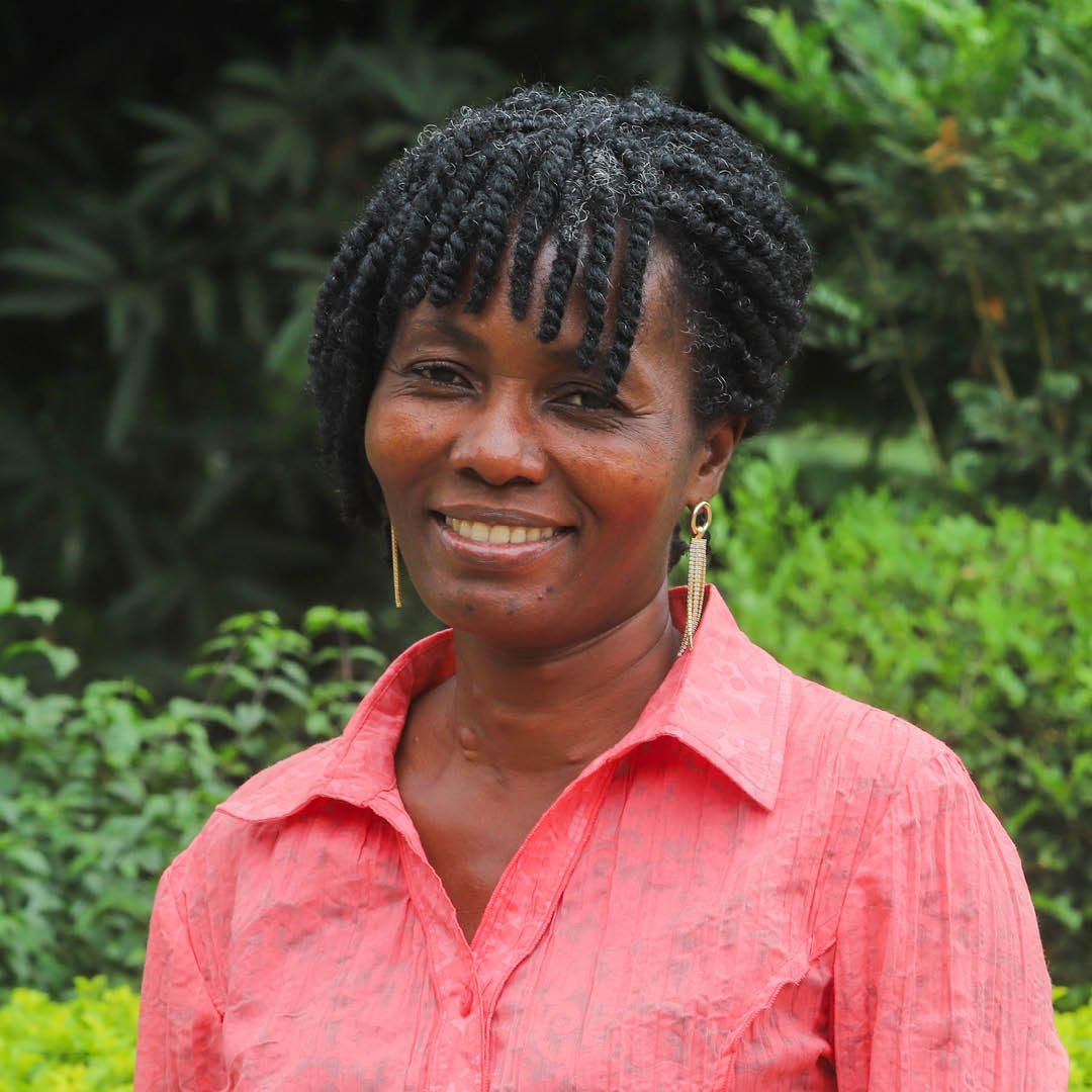 A woman wearing a red shirt and earrings is smiling for the camera.