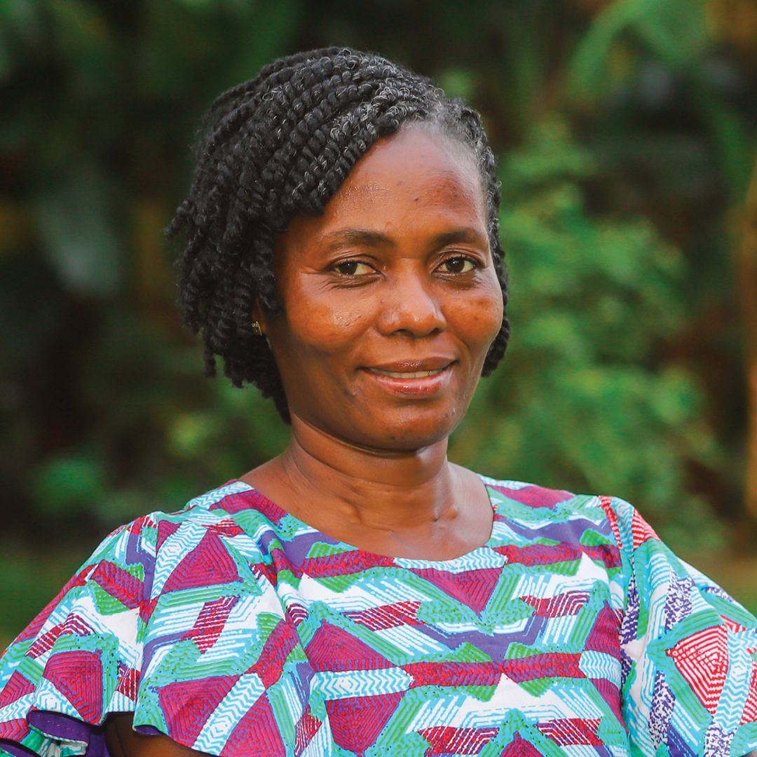 A woman wearing a red shirt and earrings is smiling for the camera.