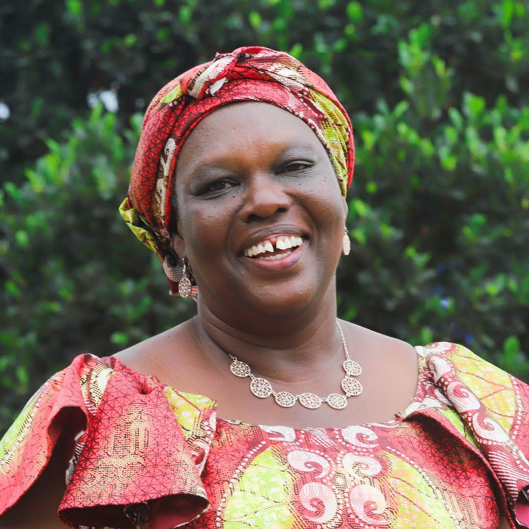 A woman wearing a turban and a necklace is smiling for the camera.