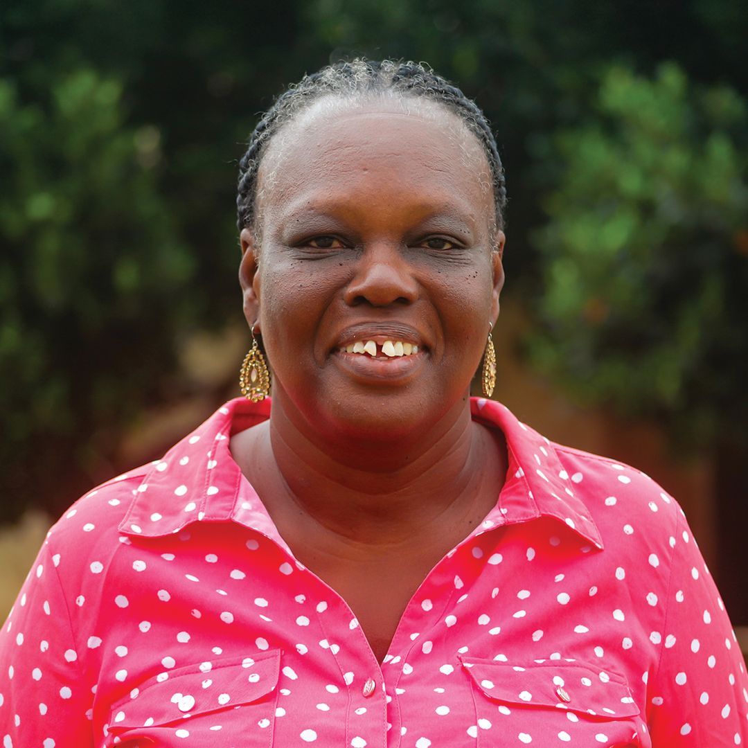 A woman wearing a turban and a necklace is smiling for the camera.