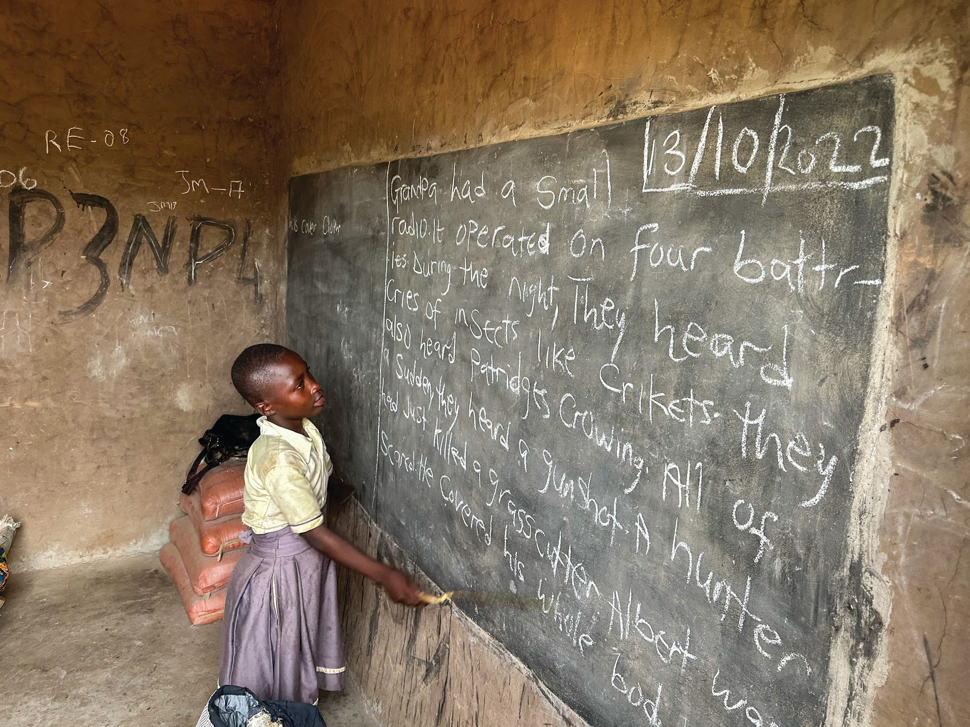 A girl writes on a blackboard with the date 13/10/22