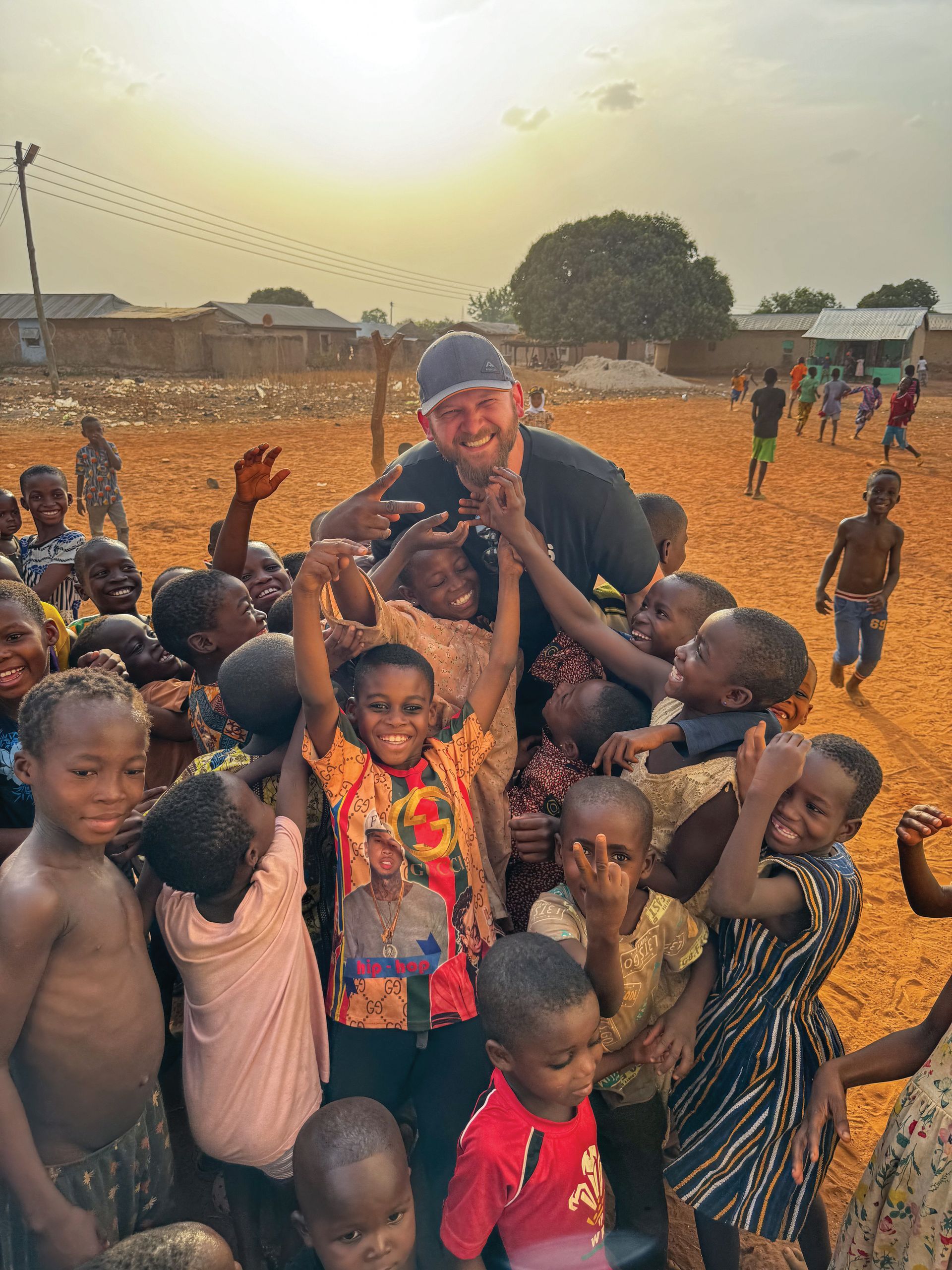 A man is standing in the middle of a group of children.