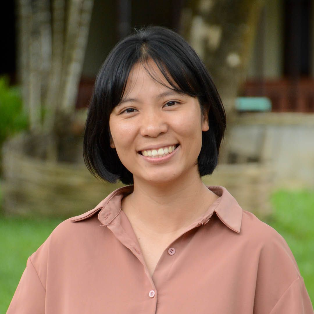 A woman in a brown shirt is smiling for the camera.