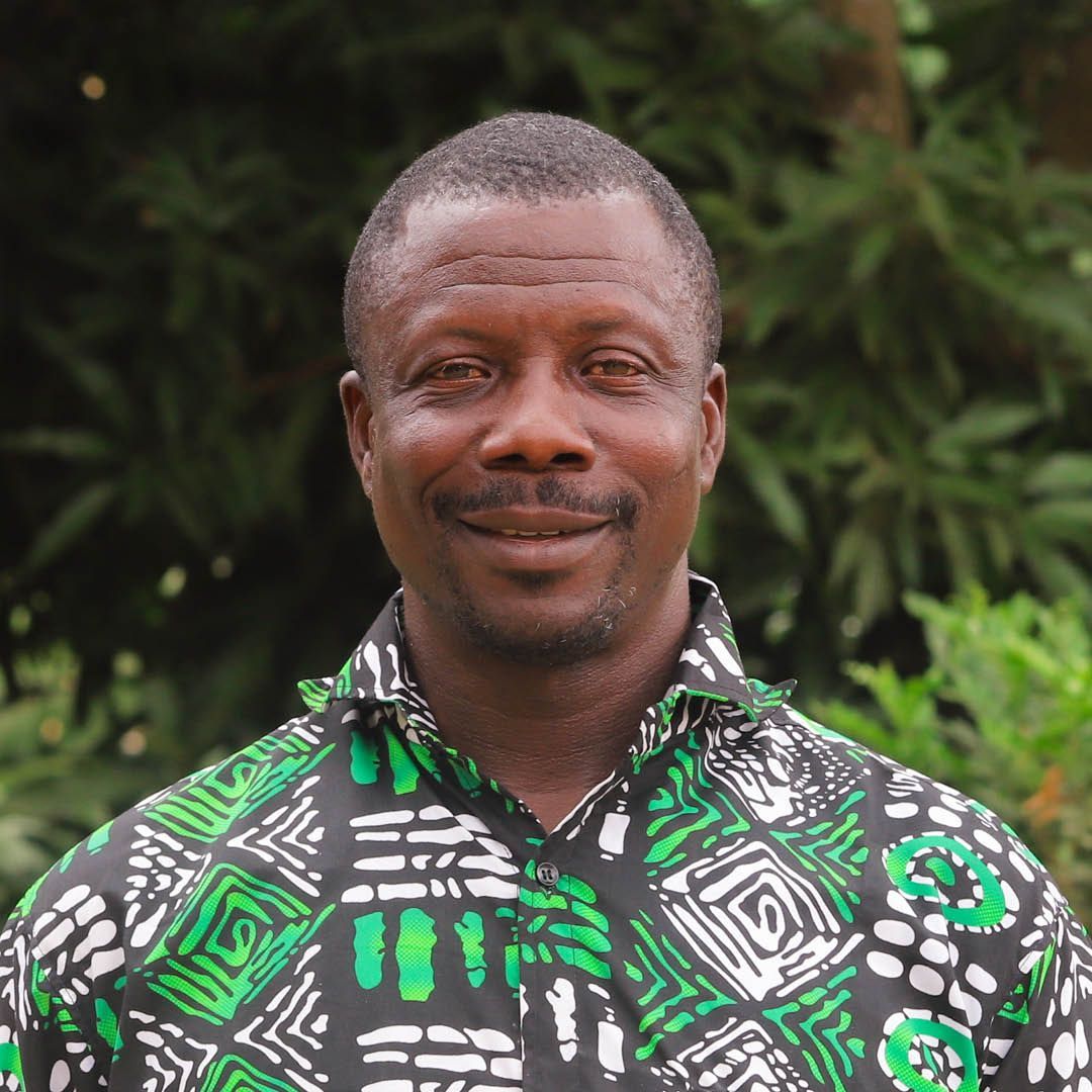 A man wearing a green and black shirt is smiling for the camera.