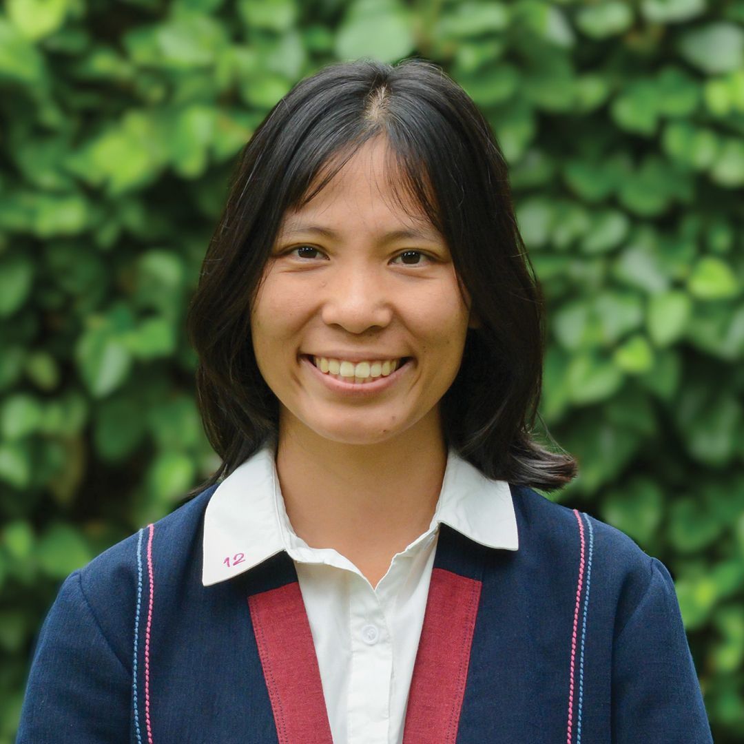 A woman in a brown shirt is smiling for the camera.