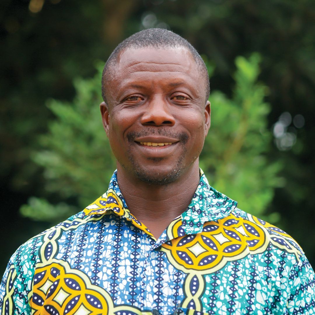 A man wearing a green and black shirt is smiling for the camera.